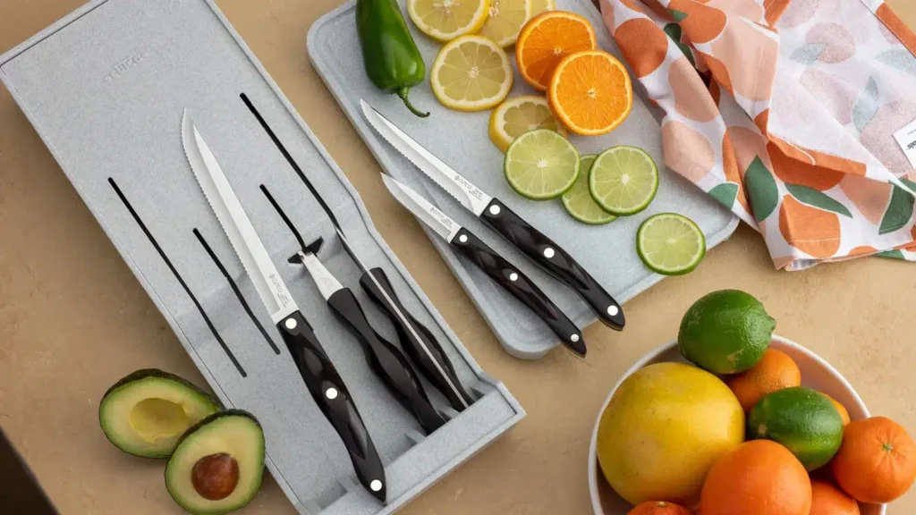 Kitchen knives with black handles on cutting boards surrounded by sliced citrus fruits