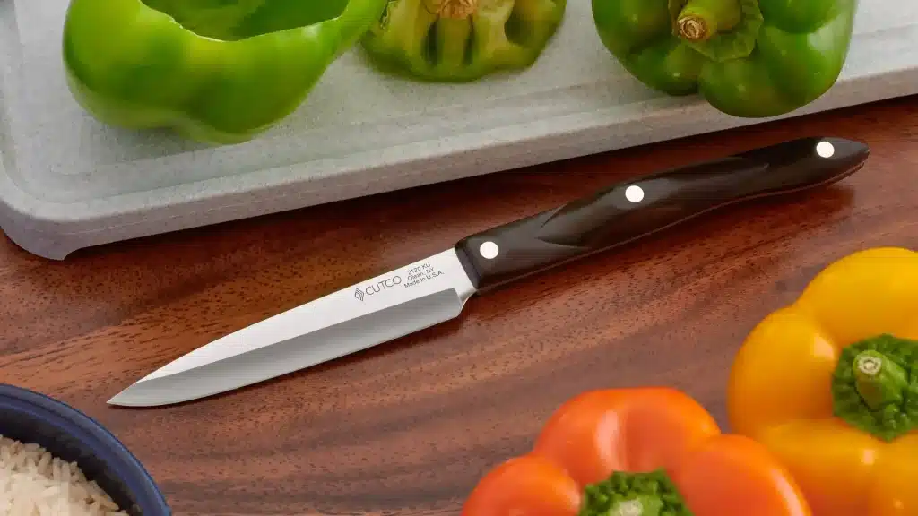 cutco paring knife on wooden cutting board with fresh bell peppers
